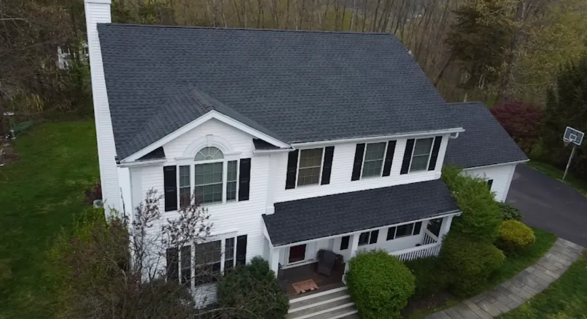 White colonial home with a new dark architectural shingle roof and black shutters